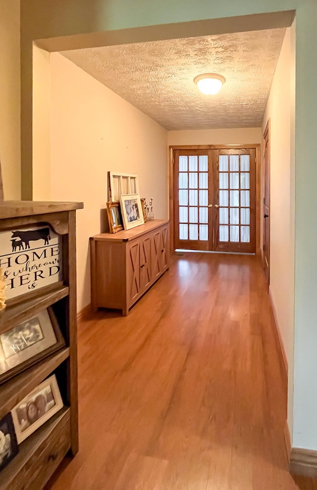 hall with french doors, hardwood / wood-style flooring, and a textured ceiling