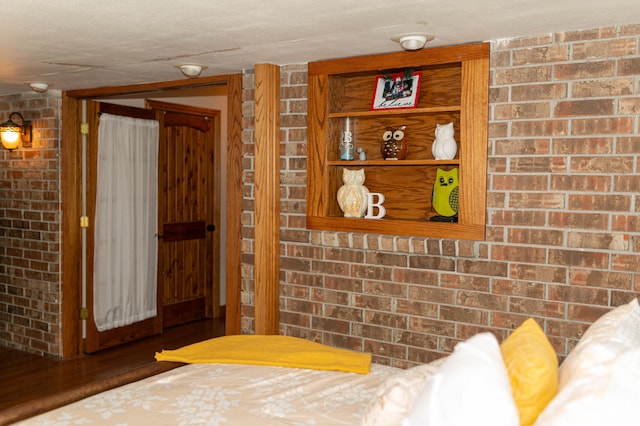 bedroom with brick wall and dark hardwood / wood-style flooring