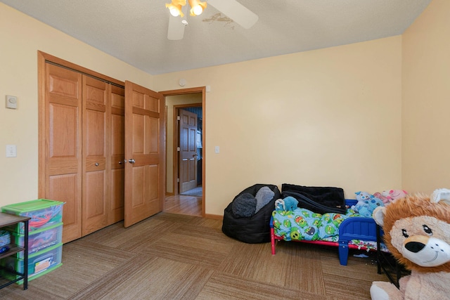 carpeted bedroom featuring a closet, a textured ceiling, and ceiling fan