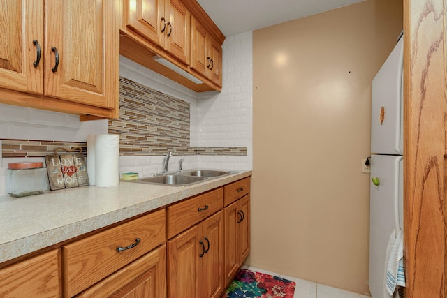 kitchen with white refrigerator, decorative backsplash, and sink