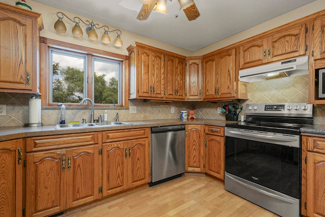 kitchen featuring appliances with stainless steel finishes, light wood-type flooring, sink, and tasteful backsplash