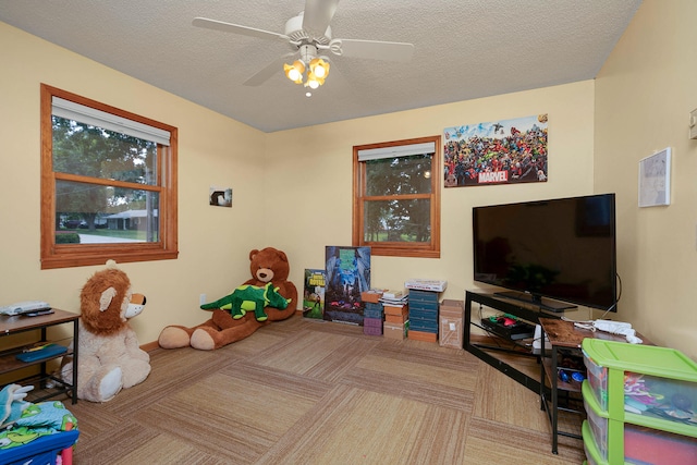 recreation room featuring ceiling fan, a textured ceiling, and carpet flooring