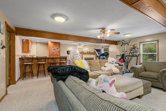 carpeted living room with bar, ceiling fan, and a textured ceiling