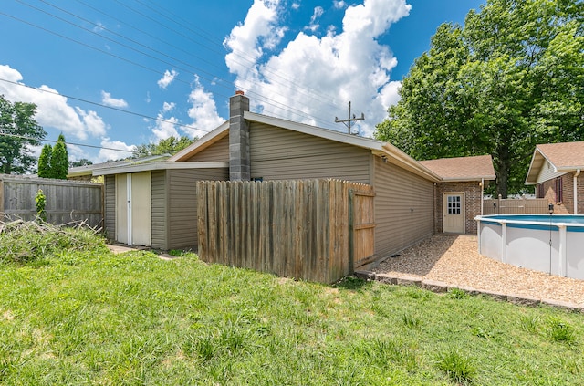 back of house with a fenced in pool, a storage shed, and a yard