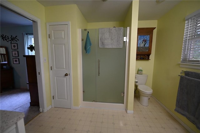 bathroom featuring a shower with door and toilet