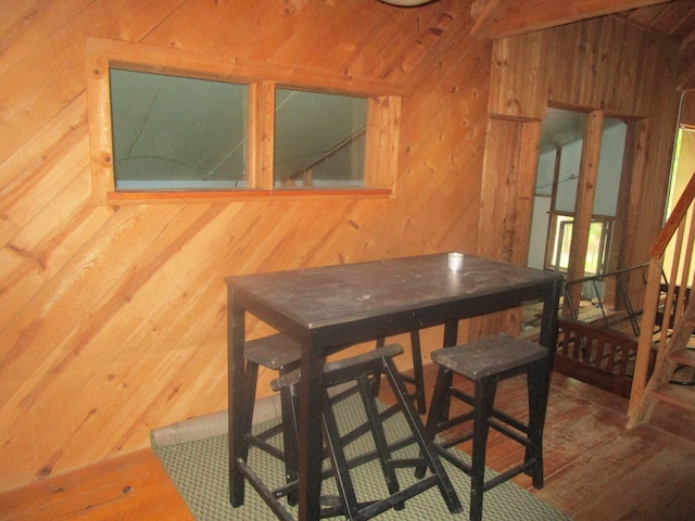 dining area with wooden walls and wood-type flooring