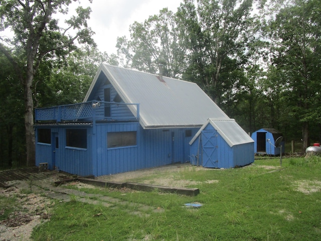 rear view of house featuring a yard and a storage unit