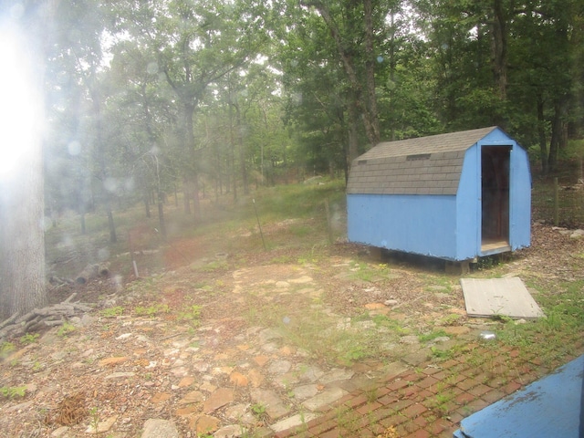 view of yard with an outbuilding, a shed, and a wooded view