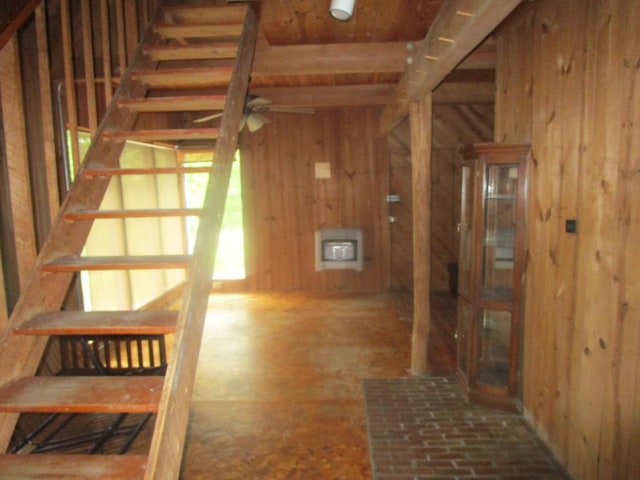 stairs with ceiling fan, wood walls, and heating unit