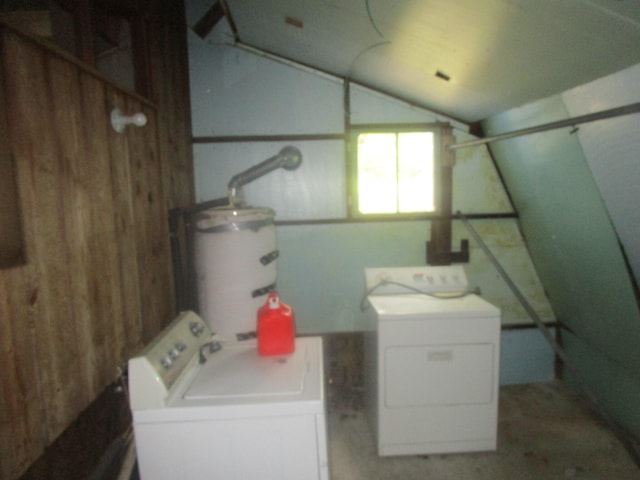 laundry area featuring secured water heater, wooden walls, and washer and clothes dryer