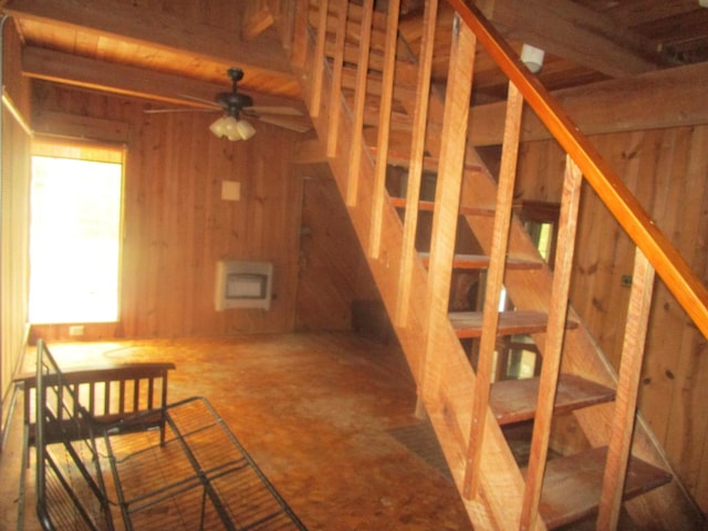 staircase with wooden walls, a ceiling fan, and heating unit