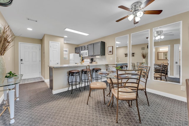 carpeted dining area with baseboards, visible vents, and ceiling fan