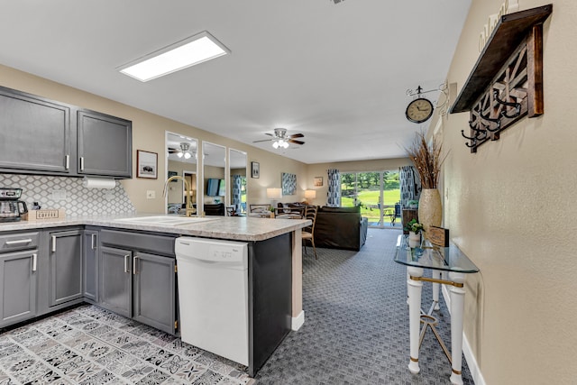 kitchen with a peninsula, a sink, white dishwasher, gray cabinetry, and a ceiling fan