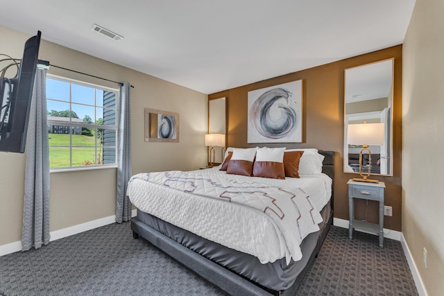 bedroom with dark colored carpet, visible vents, and baseboards