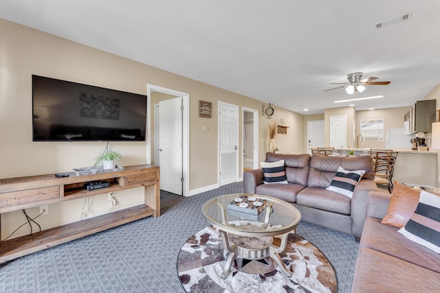 living area featuring baseboards, a ceiling fan, visible vents, and carpet floors