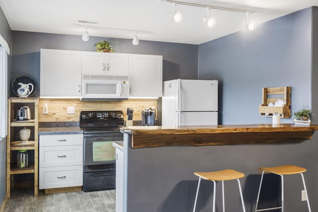 kitchen featuring white appliances, backsplash, white cabinetry, a breakfast bar area, and light wood-type flooring