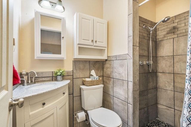 bathroom with tile walls, a shower with shower curtain, vanity, and toilet