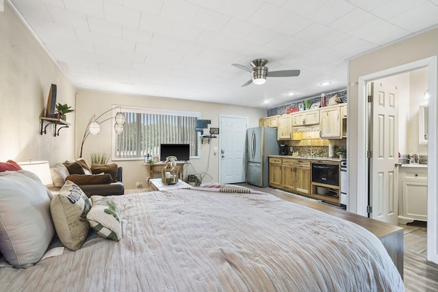 bedroom featuring wood finished floors, freestanding refrigerator, ensuite bathroom, and a ceiling fan