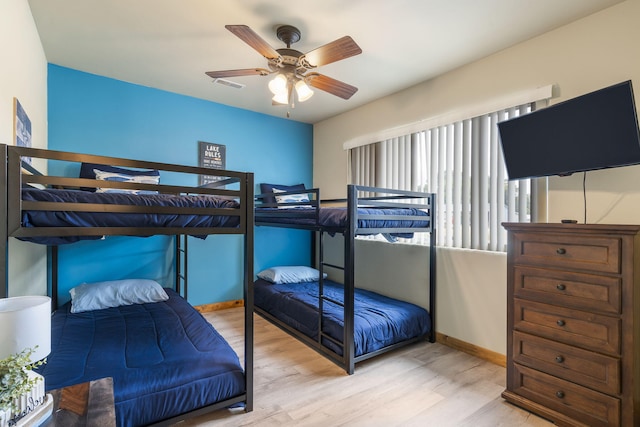 bedroom with wood finished floors, visible vents, a ceiling fan, and baseboards