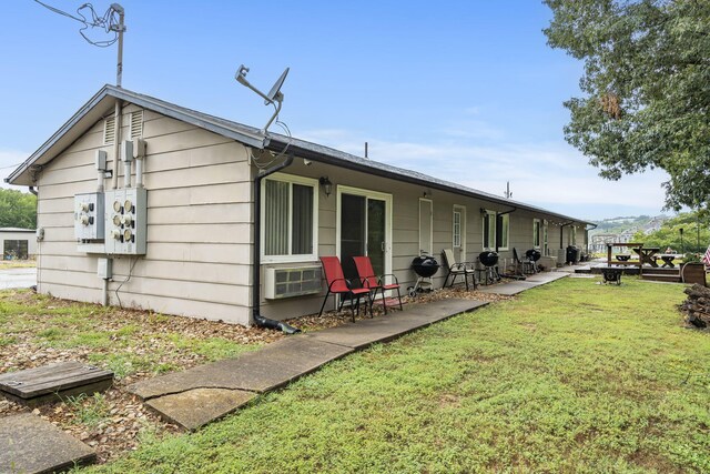 rear view of property featuring cooling unit, a lawn, and a patio