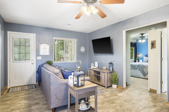 living area with visible vents, light wood finished floors, a wealth of natural light, and ceiling fan