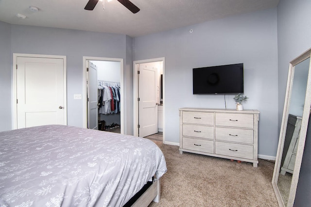 bedroom featuring a spacious closet, ceiling fan, a closet, and light colored carpet