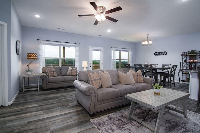 living room featuring ceiling fan with notable chandelier and dark hardwood / wood-style flooring