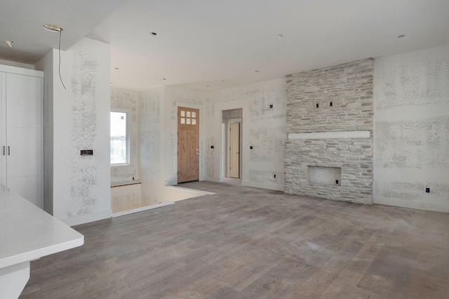 unfurnished living room with a stone fireplace and hardwood / wood-style floors