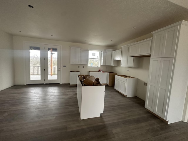 kitchen featuring dark wood-type flooring, a kitchen island, and white cabinets