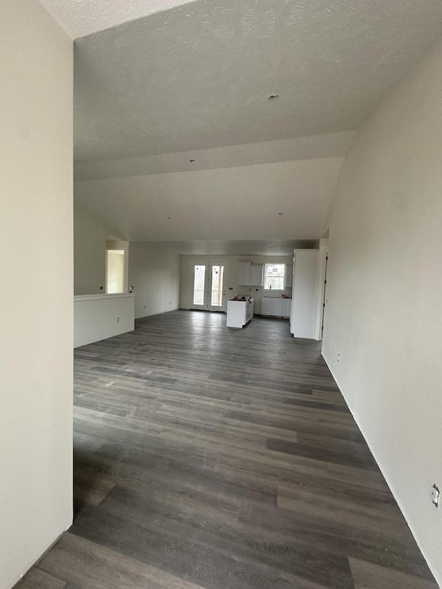 unfurnished living room with dark wood-type flooring, french doors, and a textured ceiling