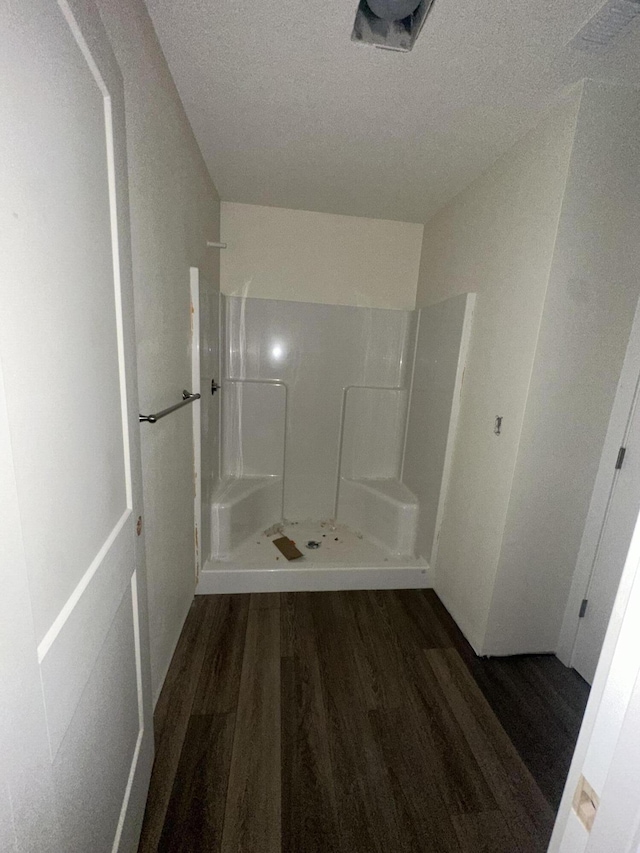 bathroom with hardwood / wood-style floors, a textured ceiling, and walk in shower