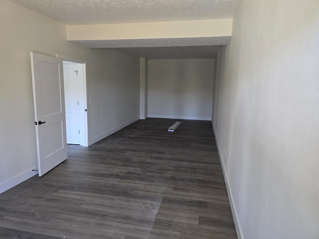 unfurnished room featuring dark wood-style floors, a textured ceiling, and baseboards