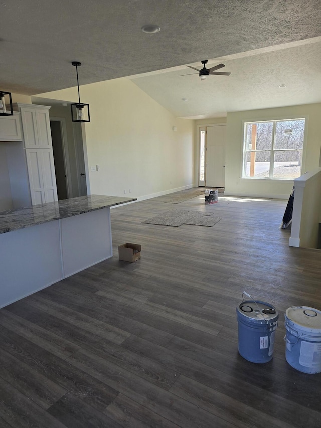 interior space with ceiling fan, baseboards, a textured ceiling, and dark wood finished floors