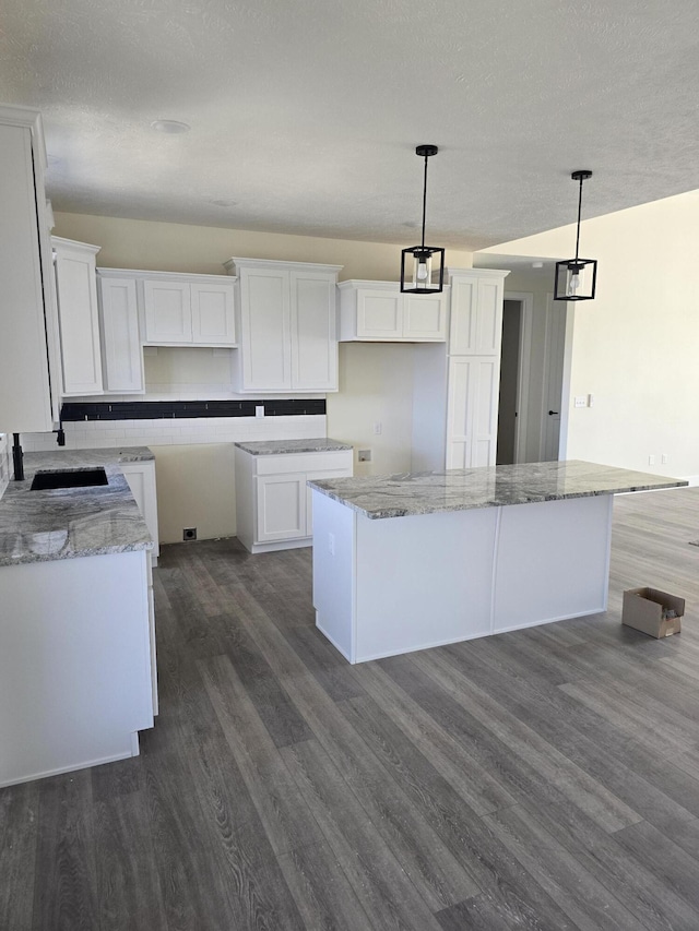 kitchen with decorative light fixtures, dark wood-style floors, and white cabinets