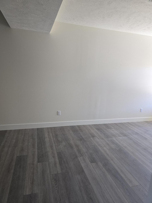 empty room with baseboards, dark wood-style flooring, and a textured ceiling