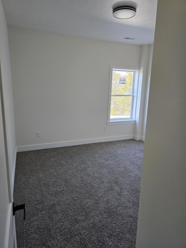 unfurnished room with visible vents, baseboards, carpet, and a textured ceiling