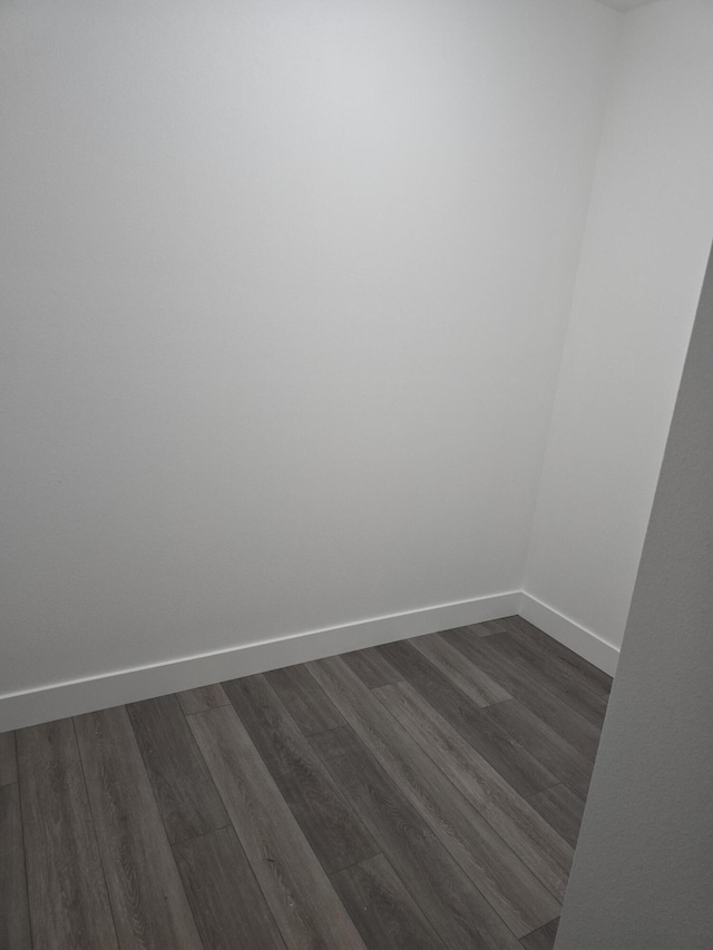 spare room with baseboards and dark wood-style floors