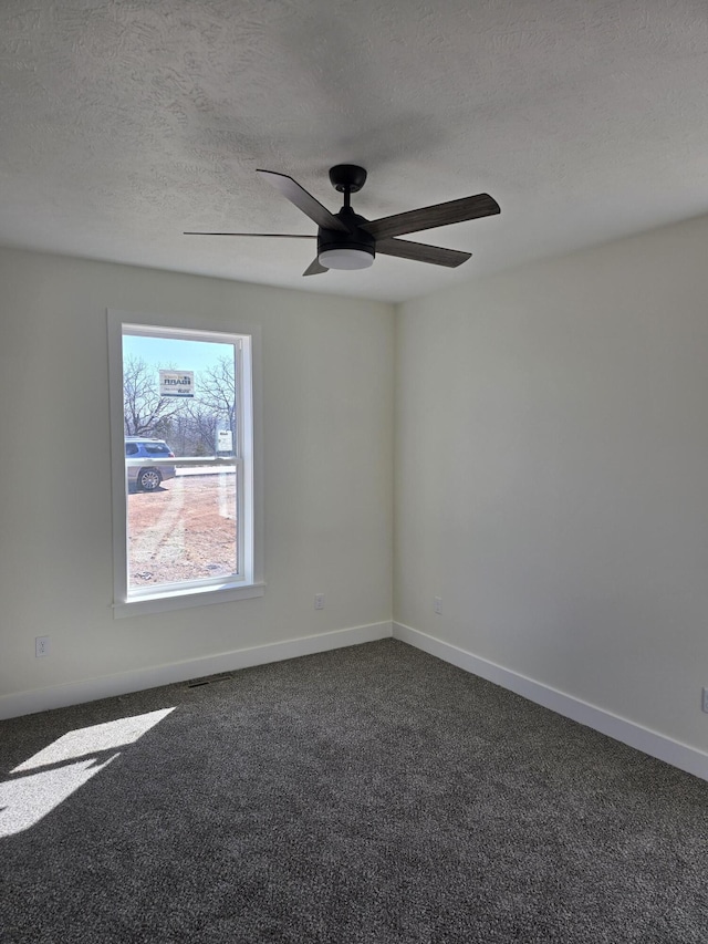 unfurnished room with a textured ceiling, a ceiling fan, baseboards, and dark colored carpet