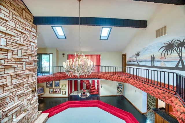 interior space with beamed ceiling, a skylight, wood-type flooring, high vaulted ceiling, and an inviting chandelier