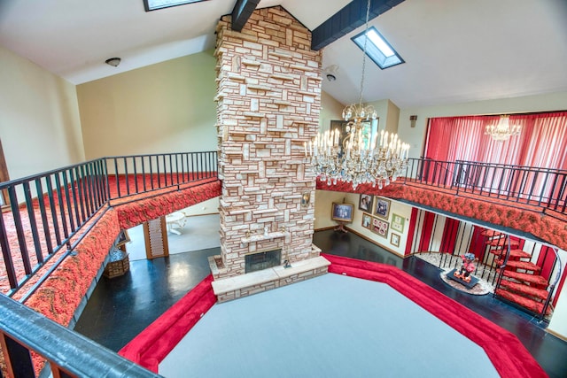 interior space featuring a stone fireplace, a notable chandelier, and lofted ceiling with skylight