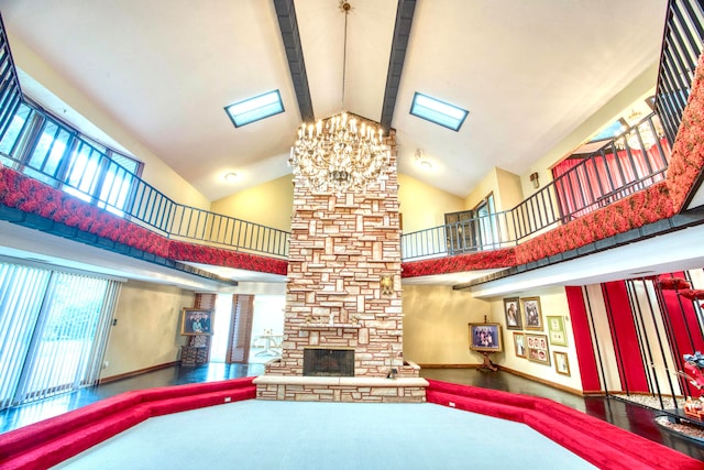 recreation room featuring a stone fireplace, beamed ceiling, a chandelier, and high vaulted ceiling