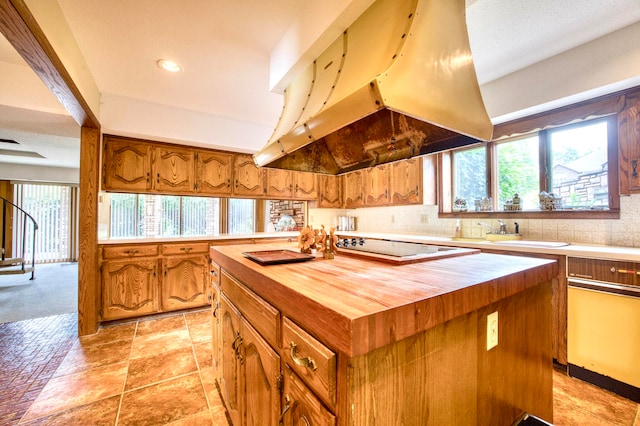 kitchen with black electric cooktop, decorative backsplash, exhaust hood, a center island, and butcher block countertops