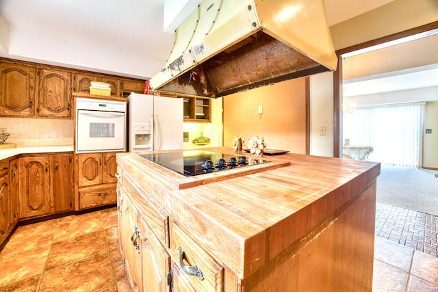 kitchen with butcher block countertops, white appliances, a center island, and backsplash