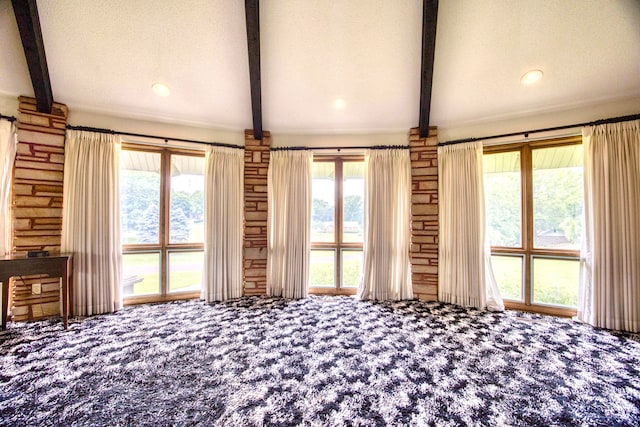 unfurnished bedroom with multiple windows, beamed ceiling, carpet, and a textured ceiling