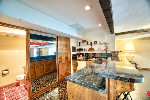 bar featuring white dishwasher, backsplash, sink, and a textured ceiling