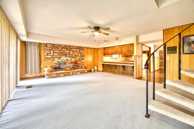 unfurnished living room with wood walls, light colored carpet, and a textured ceiling