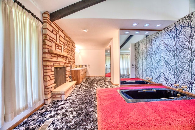 interior space featuring beamed ceiling, carpet flooring, and an outdoor stone fireplace