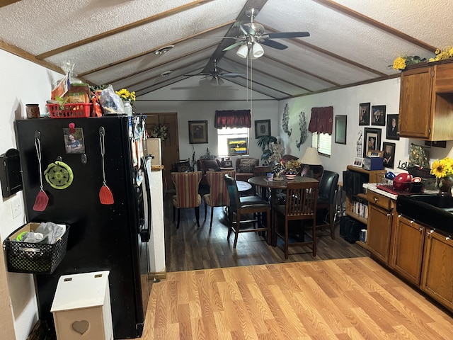 dining space featuring lofted ceiling, a ceiling fan, a textured ceiling, and light wood finished floors