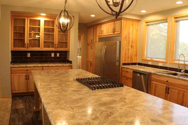 kitchen featuring decorative backsplash, dark hardwood / wood-style floors, stainless steel appliances, sink, and hanging light fixtures