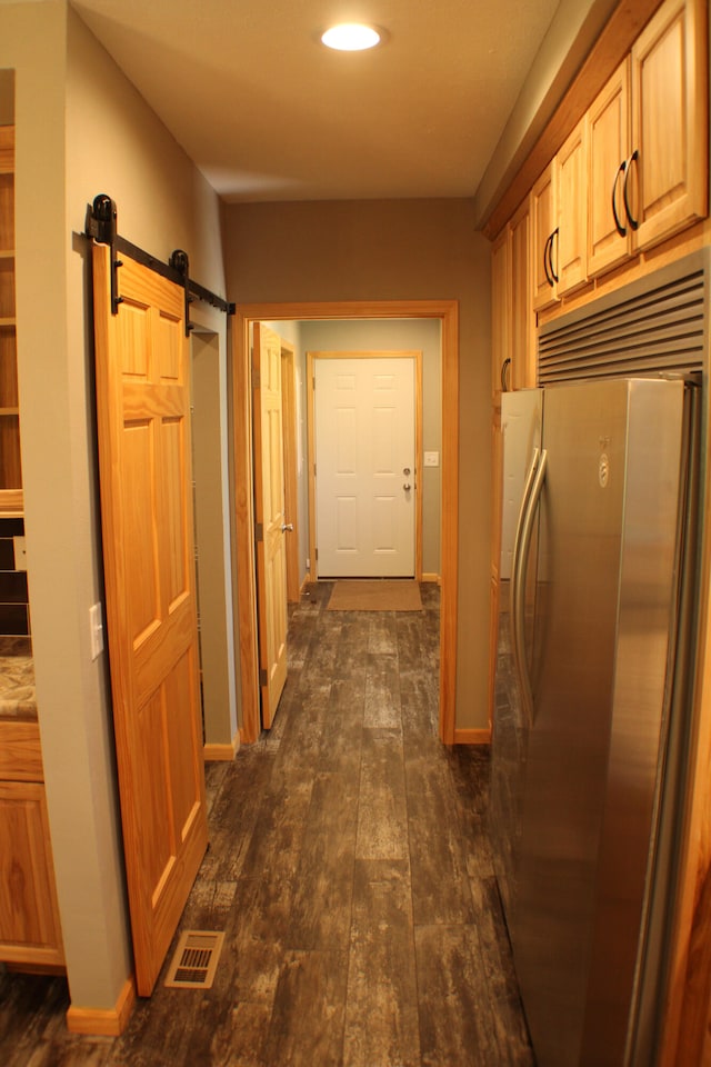 hallway with dark wood-type flooring and a barn door